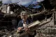 A woman collects wood for heating from a destroyed school wh