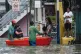 Residents use a boat to cross flooded streets caused by Trop